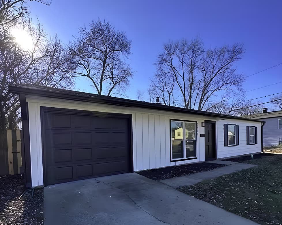 Single-story white house with black trim under a clear blue sky